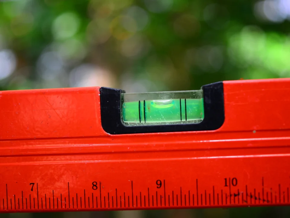 Nível de bolha vermelho em close-up mostrando a bolha centralizada entre as linhas, indicando superfície nivelada