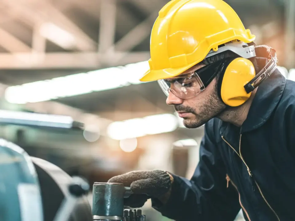 Trabalhador usando EPIs obrigatórios com ferramentas elétricas - capacete, óculos de proteção e protetor auricular